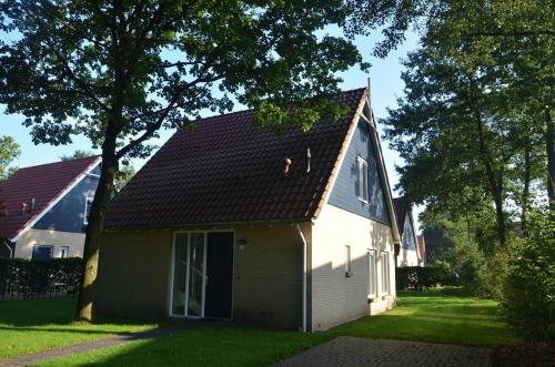 a small white house with a brown roof at Timmerholt Vakantiehuis 177 in Westerbork