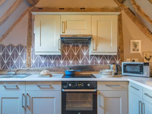 a kitchen with white cabinets and a stove top oven at Woolhouse Barn in Hunton