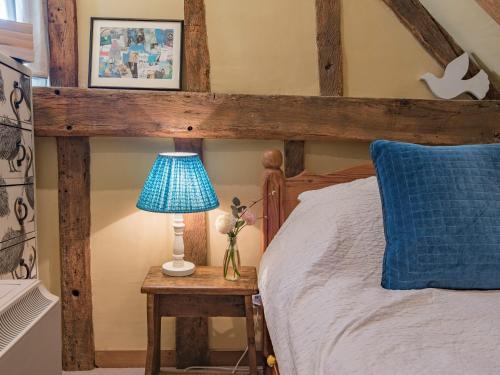 a wooden bed with a blue lamp on a table at Woolhouse Barn in Hunton