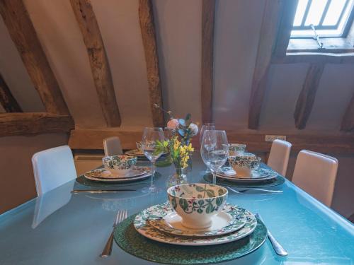 a table with plates and glasses and a vase with flowers at Woolhouse Barn in Hunton