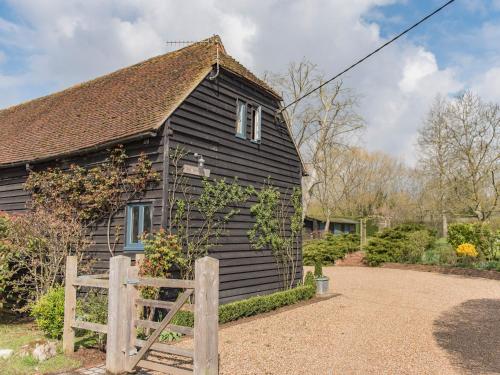 a black house with a wooden fence in front of it at Woolhouse Barn in Hunton