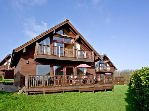 une grande maison en bois avec une grande terrasse dans l'établissement Beech Lodge - Retallack Resort, à Saint Columb Major