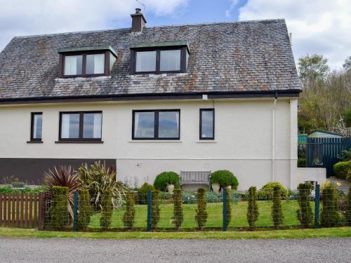 una casa blanca con ventanas negras y una valla en Seaview Cottage, en Bonnavoulin