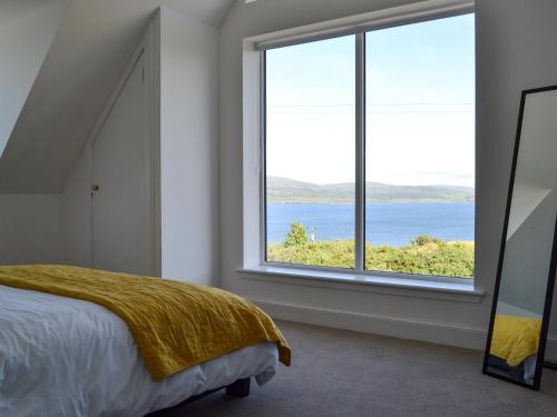 a bedroom with a large window overlooking the water at 17A Husabost in Husabost