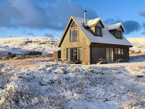 a wooden house in a snowy field with snow at 17A Husabost in Husabost