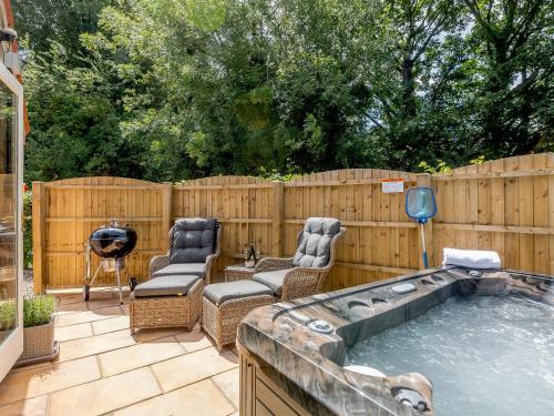 a backyard with a hot tub and chairs and a fence at The Chicken Coop in Fulletby