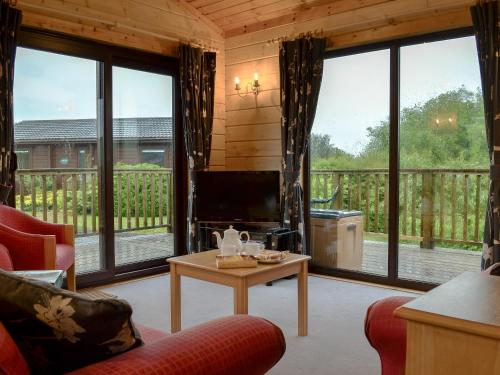 sala de estar con ventanas grandes y TV en The Brown House, en Woolfardisworthy