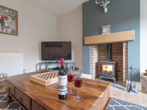 a living room with two glasses of wine and a fireplace at Abraham's Cottage in Low Eskcleth