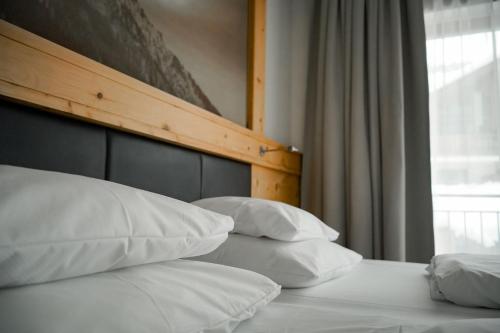 a bed with white pillows and a wooden headboard at Hotel Elisabeth, 4 Sterne Superior in Kirchberg in Tirol