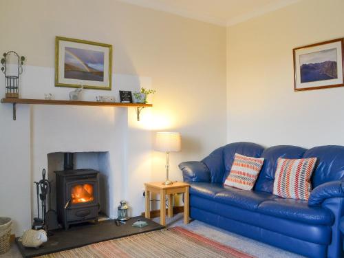 a blue couch in a living room with a fireplace at Tote Cottage in Skeabost