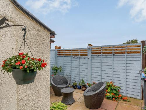 a patio with three chairs and a pot of flowers at Margaret House in Chirnside