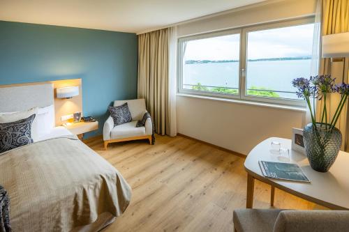 a hotel room with a bed and a desk and window at Seehotel am Kaiserstrand in Lochau