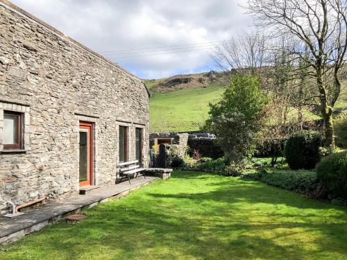 a stone house with a green yard next to a building at Yew Tree Farm in High Newton