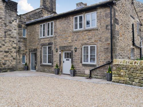 a stone house with a white door and windows at Cooper Cottage in Addingham