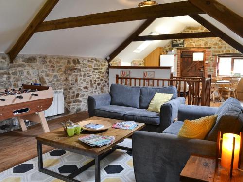 a living room with two couches and a table at The Old Coach House in Woolfardisworthy