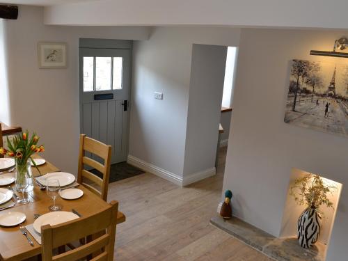 a dining room with a table and a fireplace at Cooper Cottage in Addingham