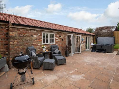 a patio with a bbq and chairs and a grill at The Shambles in Fulletby