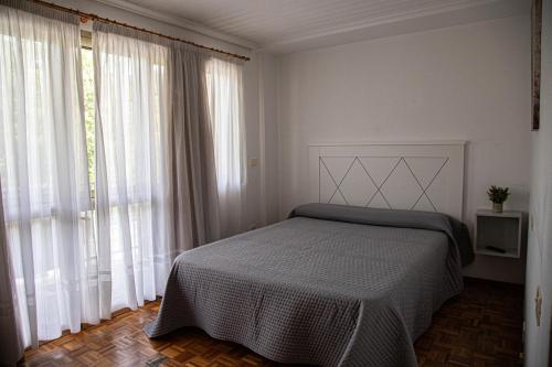 a bedroom with a bed and large windows at Garden Lodge Hostal Evencio in Ribadavia
