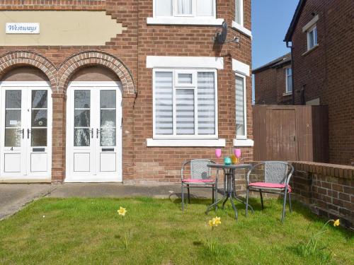 Una mesa y sillas frente a un edificio de ladrillos. en Westways, en Bridlington