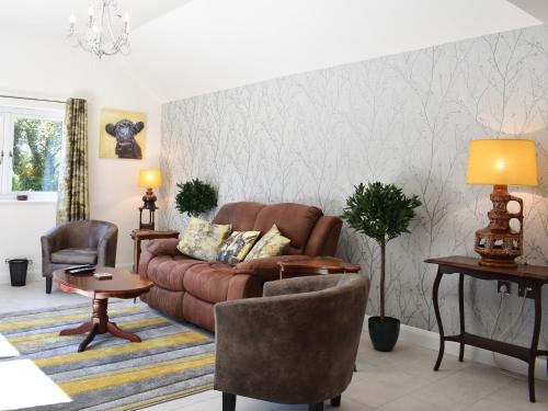 sala de estar con sofá marrón y sillas en Trees Annexe, en Gurnard