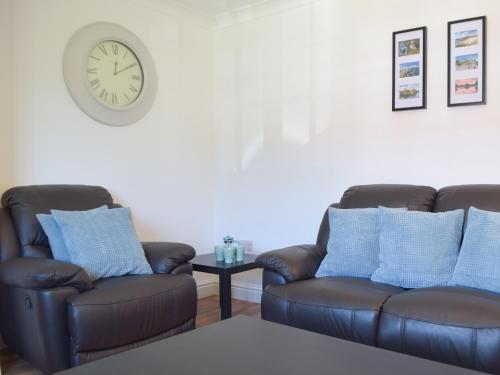 a living room with two chairs and a clock on the wall at Pembroke Cottage in Pembroke