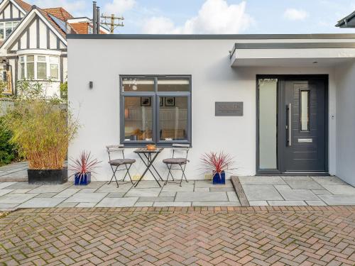 a white house with a black door and chairs at Solsken in Bournemouth