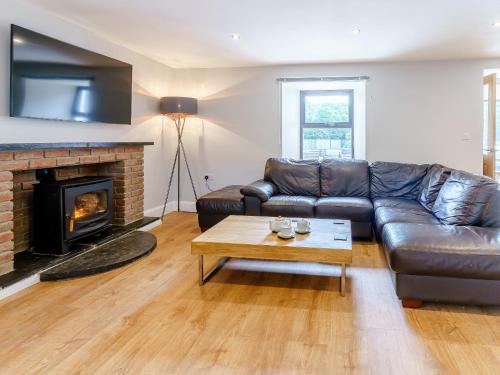 ein Wohnzimmer mit einem Ledersofa und einem Kamin in der Unterkunft Cwmporthman Farm Cottage-Uk34701 in Blaenporth