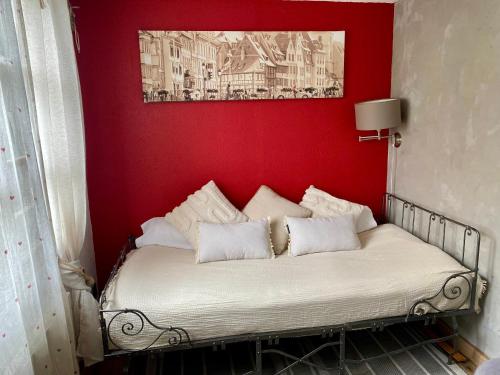 Ce lit se trouve dans une chambre dotée d'un mur rouge. dans l'établissement Appartement de caractère au calme 15 mins quartier historique, Gîte du Merlenchanteur, à Schiltigheim