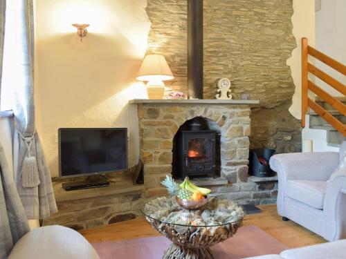 a living room with a stone fireplace and a television at Hay Barn - Dinas Country Club in Dinas