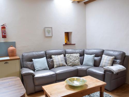 a living room with a leather couch and a table at Old Rectory Cottage - Dinas Country Club in Dinas