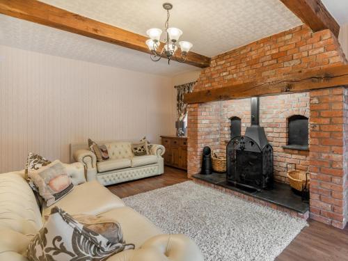 un soggiorno con camino in mattoni e divano di Highfield Cottage a Hambleton