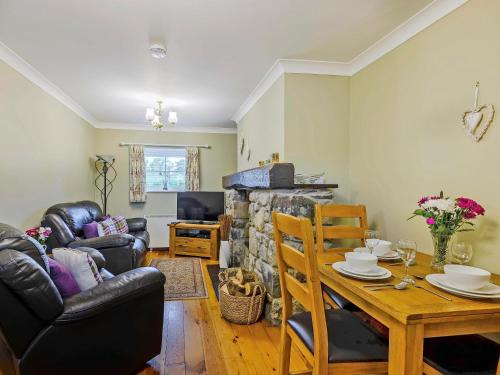 a living room with a table and a fireplace at Bwthyn - Uk31387 in Caeathro