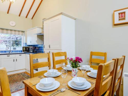 a kitchen and dining room with a wooden table and chairs at Ysgubor - Uk31389 in Caeathro