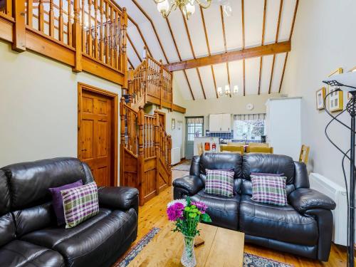 a living room with two leather couches and a table at Ysgubor - Uk31389 in Caeathro