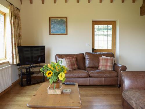 a living room with a couch and a table with flowers at Talog Barn-Uk31366 in Tregynon