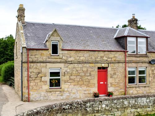 a stone house with a red door at The End Hoose in Whitsome