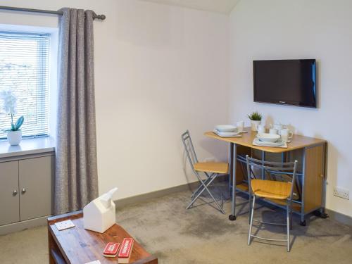 a room with a table and chairs and a television at The Cottage in Girvan