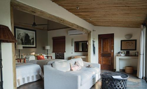 a bedroom with two beds and a living room with a couch at Mashatu Lodge in Lentswelemoriti