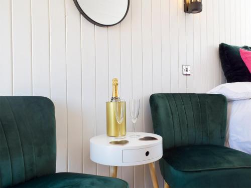two green chairs and a table with a bottle of champagne at Twin Oaks in Crudgington