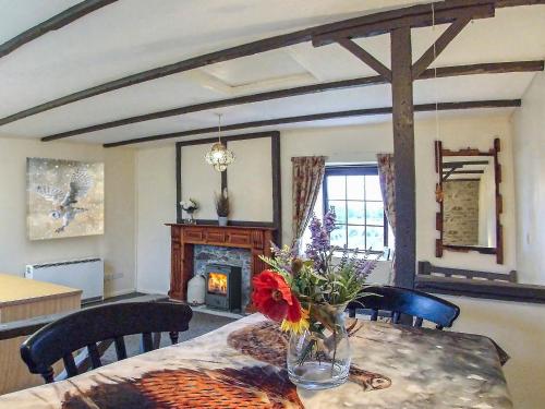 a dining room with a table with a vase of flowers at Sage Cottage in Truro