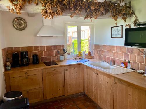 a kitchen with wooden cabinets and a sink and a window at Les gîtes du Tilleul de Cassel in Cassel