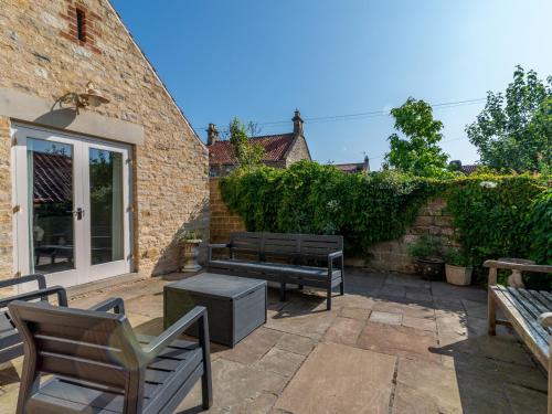 a patio with two benches and a brick wall at The Cart House in Helmsley