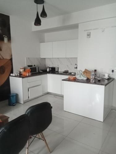 una cucina con mobili bianchi e un piano di lavoro nero di Sunworld Arista T10 ,906 a Noida