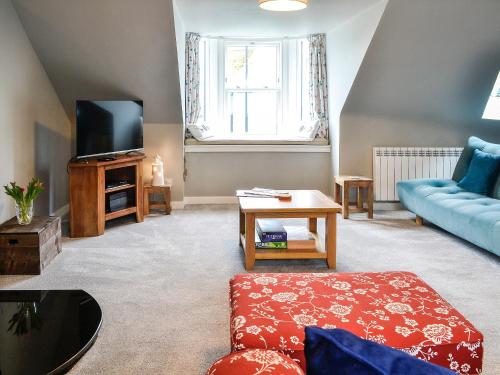 a living room with a blue couch and a tv at The Old Toll House in Portpatrick