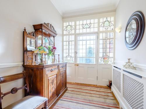 a living room with a large wooden cabinet and windows at The Bield in Aberfoyle