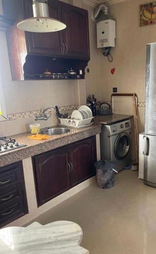 a kitchen with a sink and a washing machine at Calme, plage 8 min, tout proche in Temara