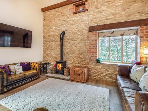 a living room with a brick wall and a fireplace at Coach House in Rowston