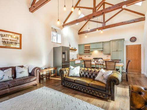 a living room with two couches and a kitchen at Coach House in Rowston