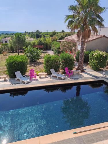 - une piscine avec des chaises et un palmier dans l'établissement Rêve et Soleil, à Adissan