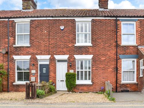 una casa in mattoni rossi con porte e finestre bianche di Daisy Cottage a Sea Palling